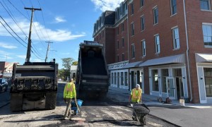 Asphalt paving crew working on road surface near commercial buildings in Bethlehem NY