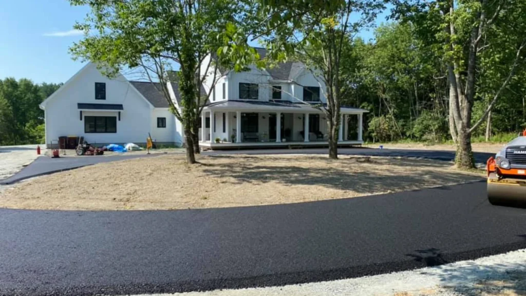 A white house with a brand new asphalt driveway and sealcoat application