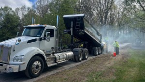J. Hunziker dump truck actively laying asphalt with steam rising on a job in Rotterdam, NY