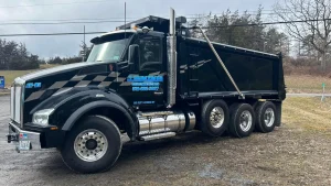 A black J. Hunziker Asphalt Paving dump truck parked in a parking lot